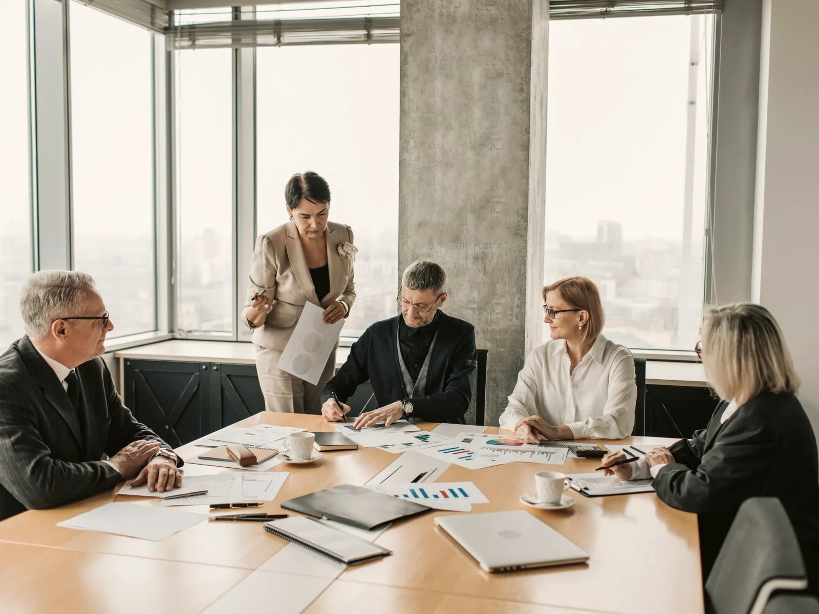Professional services leaders reviewing printed financial charts at a conference table
