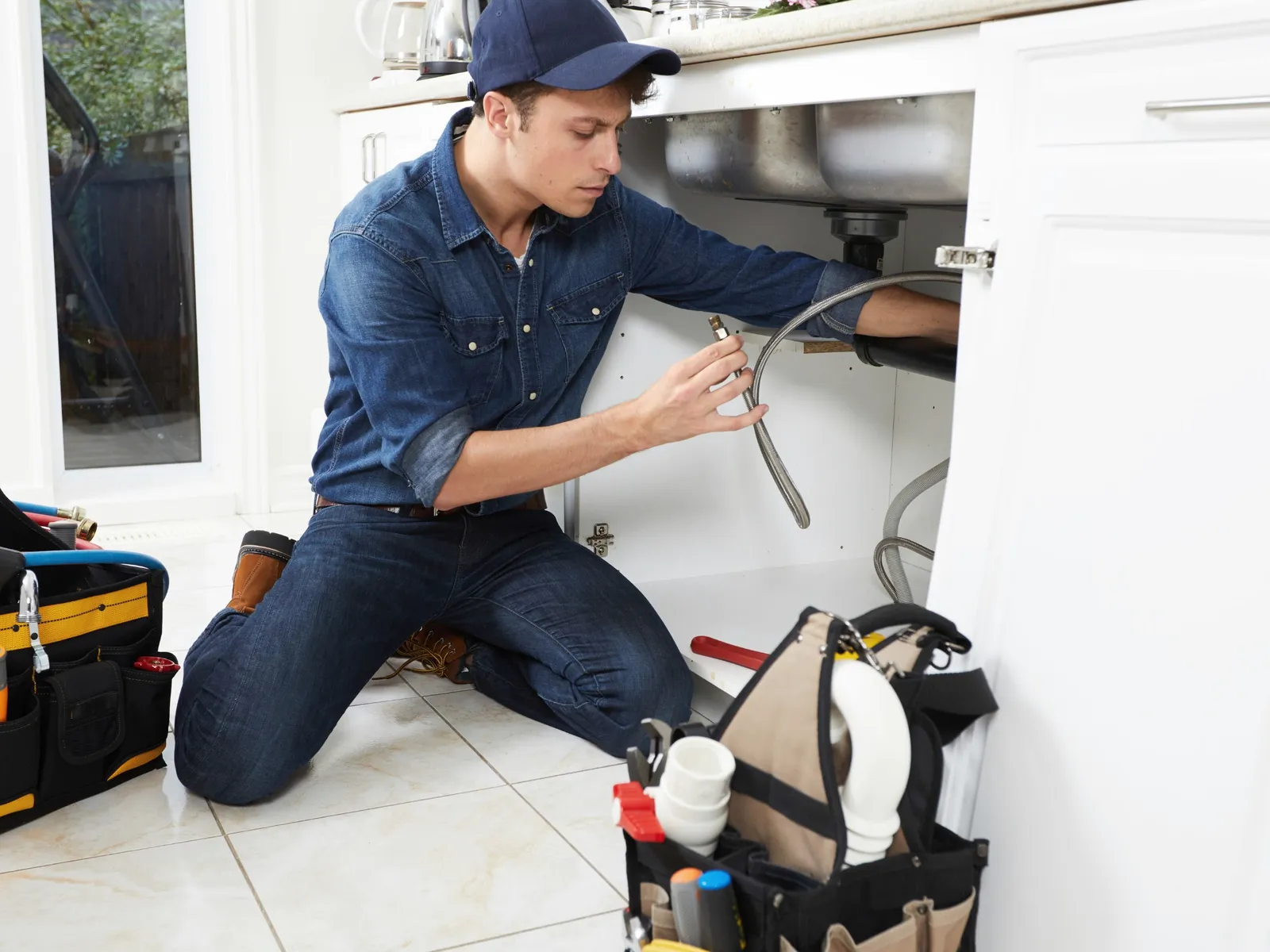 Plumber repairing the pipes under a kitchen sink